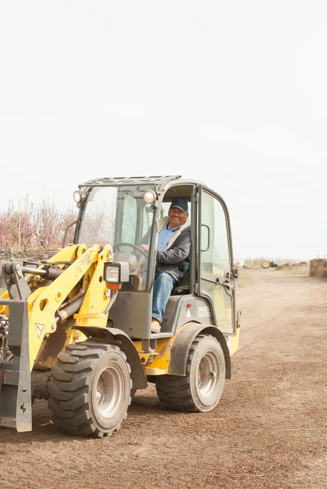 Team member smiling from the cab of a yellow wheel loader